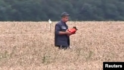 격추된 말레이시아 항공기의 비행기록장치로 보이는 물건을 구조대원이 들고가는 모습. 지난 18일에 촬영된 동영상에 담긴 장면이다.