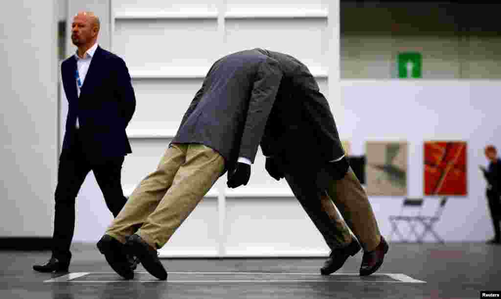 A man walks past the artwork "Infinity Head" by U.S. street artist Mark Jenkins, at the Cologne Fine Art Fair, in Cologne, Germany.