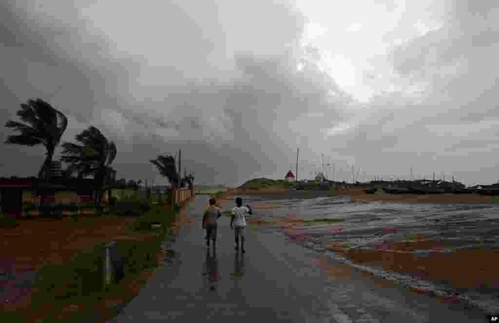 Two villagers walk along the Bay of Bengal coast at Gopalpur, Orissa, Oct. 12, 2014.
