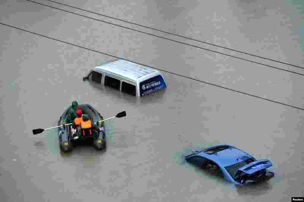 Sebuah perahu penyelamat mendekati dua mobil yang terendam banjir akibat hujan deras di kota Guiyang, Guizhou, China.
