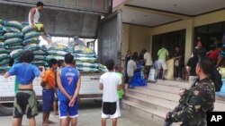 Seorang tentara mengawasi pembongkaran pasokan beras untuk warga yang mengungsi akibat topan Hagupit di kota Tacloban, Filipina (5/12). 