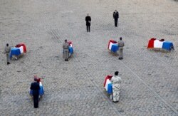 French President Emmanuel Macron pays his respect in front of the flag-draped coffins of the thirteen French soldiers killed in Mali, during a ceremony at the Hotel National des Invalides in Paris, Dec. 2, 2019.