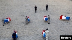 FILE - French President Emmanuel Macron pays his respect in front of the flag-draped coffins of the thirteen French soldiers killed in Mali, during a ceremony at the Hotel National des Invalides in Paris, France, Dec. 2, 2019.