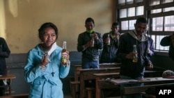 Des étudiants boivent des bouteilles de Covid Organics, une tisane, présentée par le président malgache Andry Rajoelina comme un puissant remède contre le coronavirus COVID-19 à Madagascar.