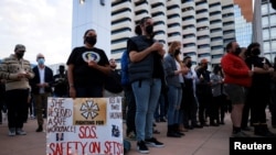A woman displays a sign calling for workplace safety at a vigil for cinematographer Halyna Hutchins, who died after being shot by Alec Baldwin on the set of his movie "Rust", in Albuquerque, New Mexico, October 23, 2021. 
