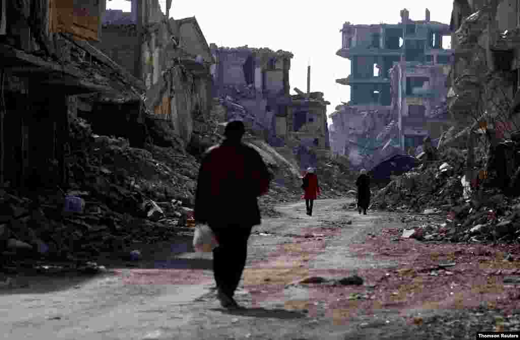 시라아 다마스쿠스의 '야묵(Yarmouk)' 팔레스타인 난민 캠프의 부서진 건물들 사이로 사람들이 걷고 있다.