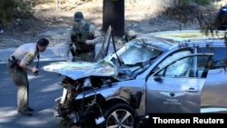 FILE - Los Angeles County Sheriff's Deputies inspect the vehicle of golfer Tiger Woods, who suffered multiple injuries in a single-vehicle crash in Los Angeles, California, Feb. 23, 2021. 