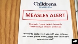 In this May 2, 2017 photo, a sign at the specialty clinic at Children's Minnesota in Minneapolis, alerts patients to a measles outbreak in the area. 