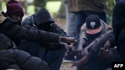 Des migrants soudanais attendent près d'un feu dans la forêt à Ouistreham, France, le 5 octobre 2017.