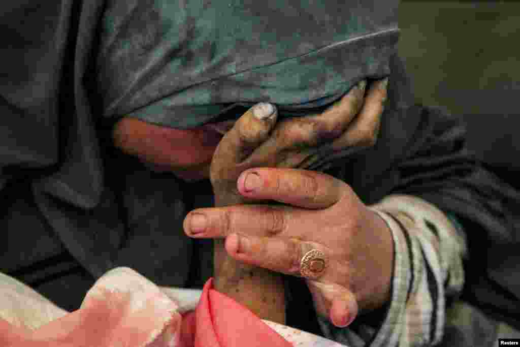 Palestinian woman Buthayna Abu Jazar reacts as she holds the hand of her son Hazma, who was killed in an Israeli strike in Rafah in the southern Gaza Strip amid the ongoing conflict between Israel and Hamas, May 9, 2024.