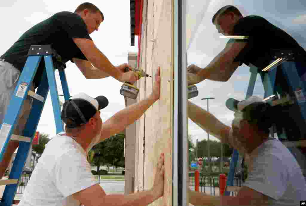 Justin Davis, left, and Brock Mclean board up a business in advance of Hurricane Michael in Destin, Florida, Oct. 9, 2018.