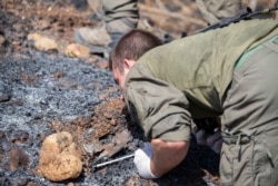 An Israeli soldier examines the remains of a rocket near the village of Avivim on the Israel-Lebanon border, Sept. 2, 2019.