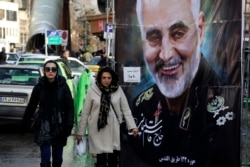 Women walk past a banner of Iranian Revolutionary Guard Gen. Qassem Soleimani, who was killed in Iraq in a U.S. drone attack, in Tajrish square in northern Tehran, Iran, Jan. 9, 2020.