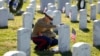 FILE - A female U.S. Marine touches the grave of a friend at Arlington National Cemetery in Virginia.