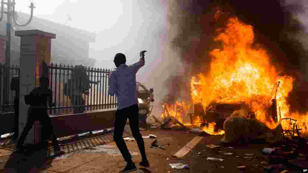 A car burns outside the parliament building in Burkina Faso as people protest against their longtime President Blaise Compaore who seeks another term in Ouagadougou, Burkina Faso, Oct. 30, 2014.