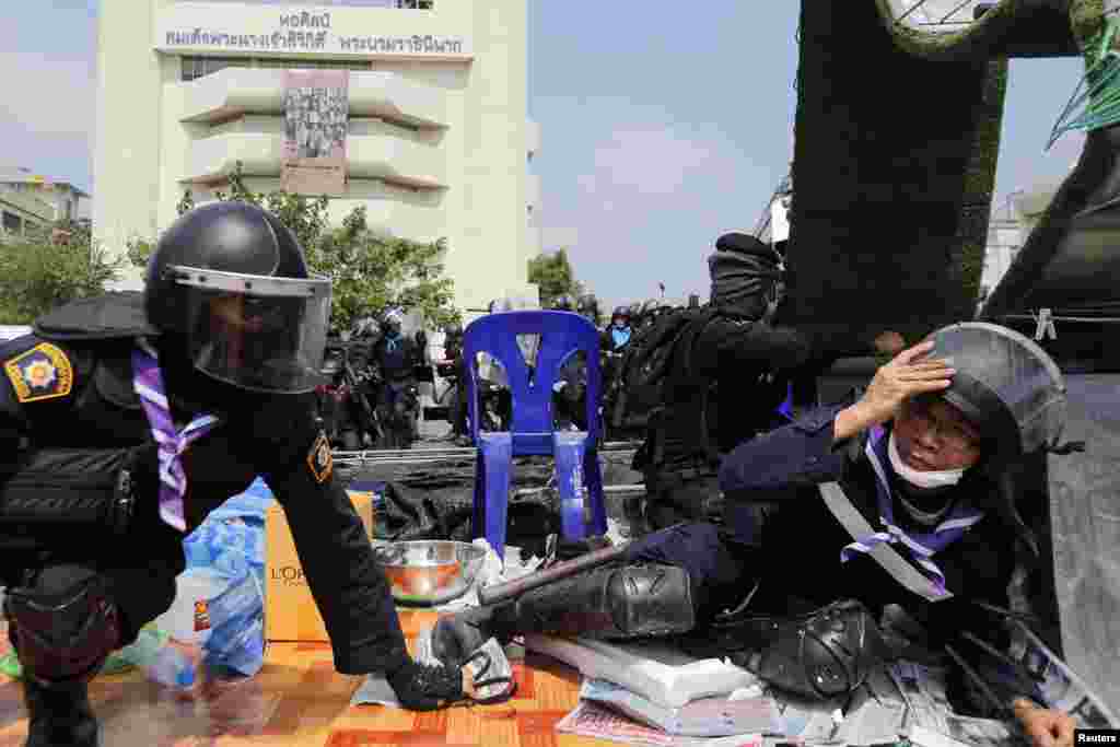 Policemen take cover as shots are fired during clashes with anti-government protesters near the Government House in Bangkok, Feb. 18, 2014.