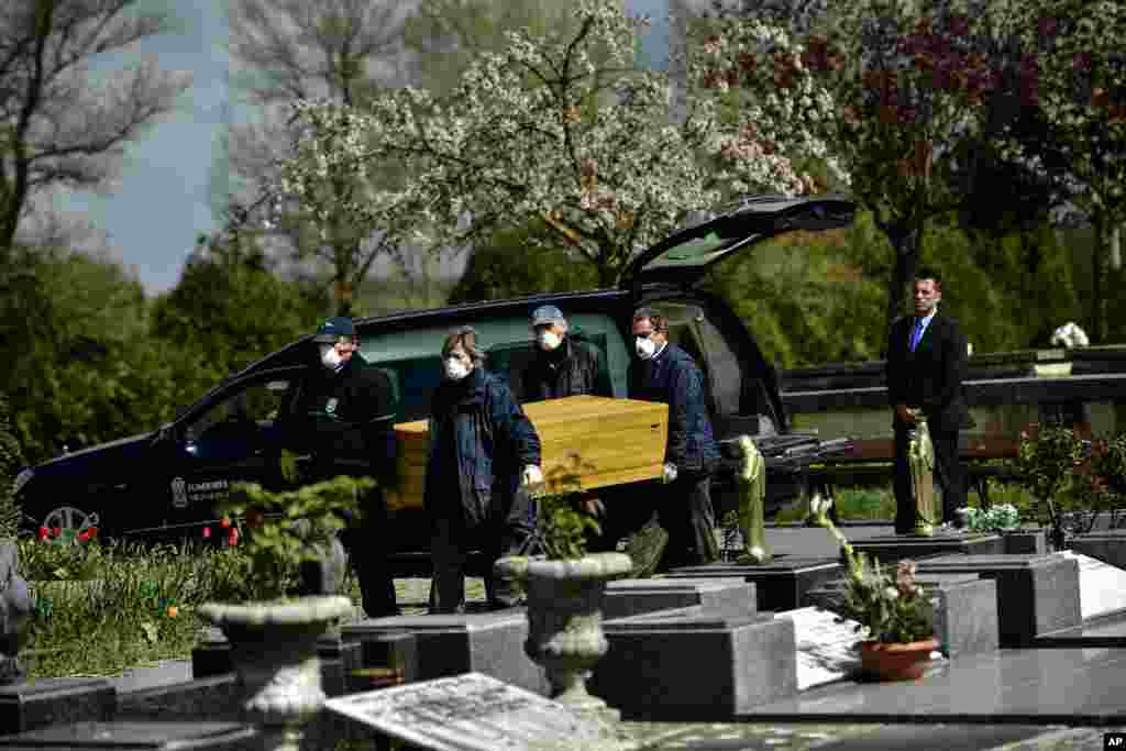 Personas con máscaras de protección para protegerse del coronavirus, cargan un ataúd en el cementerio Salvador, cerca de Vitoria,al norte de España.