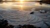 FILE - The sun rises above a polluted lake at the Nam Son garbage dump, north of Hanoi, Vietnam.