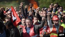 Workers on strike are evacuated by French riot policemen as they block the access to an oil depot near the Total refinery of Donges, western France, to protest against the government's planned labor law reforms on May 27, 2016.