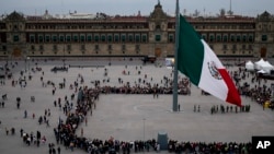 La gente observa la ceremonia de izamiento de la bandera en el Zócalo de la Ciudad de México, el sábado 20 de enero de 2024.