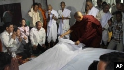 In this photo taken, Thursday, March 14, 2013, Ieng Vuth, left, a son of Ieng Sary, former Khmer Rouge foreign minister, prays with his family members near the body of his father at their home in former stronghold of Malai near the Cambodian-Thai border, some 420 kilometers (260 miles) northwest of Phnom Penh, Cambodia. Ieng Sary, who co-founded the communist Khmer Rouge regime responsible for the deaths of an estimated 1.7 million Cambodians in the 1970s, and who decades later became one of its few leaders to be put on trial, died Thursday before his case could be finished. He was 87. (AP Photo)