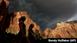Hikers look up at a fast moving storm as it makes its way through Zion National Park outside of Springdale, Utah. 
