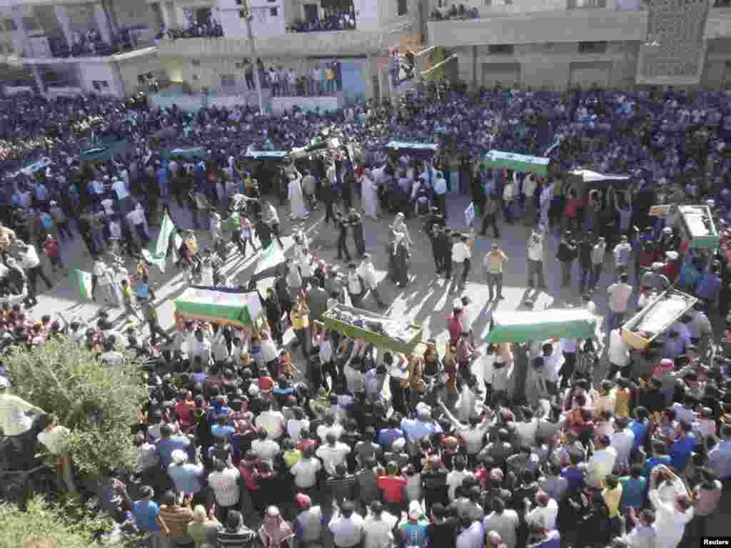 Syrian residents carry the bodies of people whom protesters say were killed by forces loyal to Syria's President Bashar al-Assad, during their funeral in Dara'a June 9, 2012.
