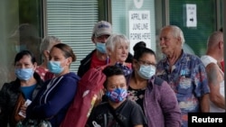 Fila de personas espera en el exterior de una oficina de ayuda para desempleados en Frankfort, Kentucky, el 18 de julio de 2020.