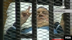 Gambar dari televisi Mesir menunjukkan mantan Presiden Hosni Mubarak memberi gerak isyarat di ruang persidangan di akademi polisi di Kairo (15/8).