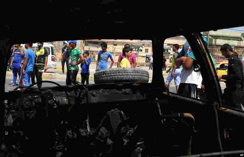 Civilians inspect the site of a car bomb explosion in the Shi'ite stronghold of Sadr City, in Baghdad, May 13, 2014.