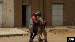 Un membre des forces armées maliennes porte un enfant blessé sur les lieux d'une explosion lors d'une "attaque terroriste" contre un poste militaire malien , à Gao dans le nord-est du pays, le 1er novembre 2019. (Photo AFP)