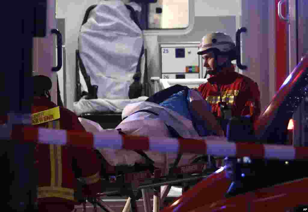 Para petugas pemadam kebakaran mengangkut korban luka ke dalam ambulans setelah sebuah truk sengaja menabrak kerumunan pasar Natal dan menewaskan beberapa orang di Berlin, Jerman (19/12). (AP/Michael Sohn)