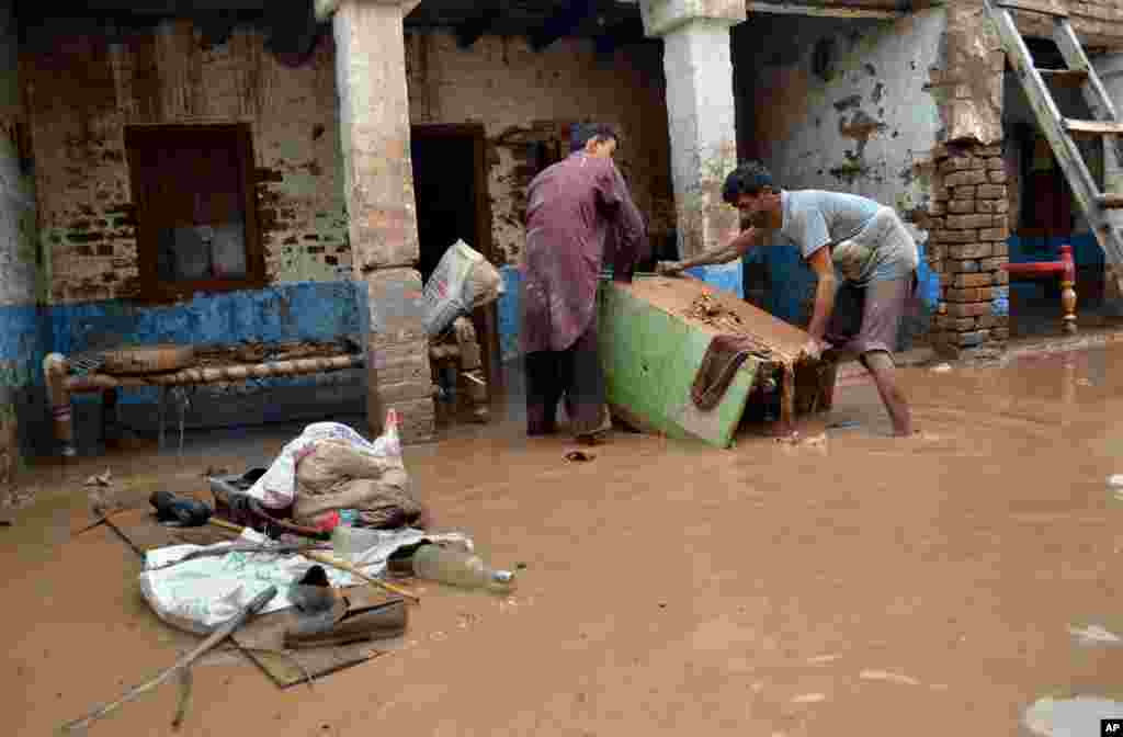 Pakistanis remove their belonging from a home flooded by heavy torrential rains in Peshawar, Pakistan, August 3, 2013. 