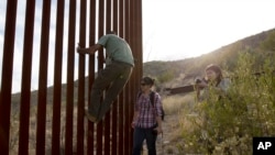 Un membre d'un groupe de surveillance à la frontière montre comment grimper cette section du mur entre l'Arizona et le Mexique, le 11 mai 2016.
