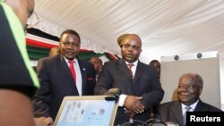 Kenyan President Mwai Kibaki (R) registers as a voter before launching the nationwide, one-month biometric voter registration exercise in the capital Nairobi on November 19, 2012, targeting over 18 million voters ahead of the March 4 election.