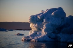 The sun sets against an iceberg floating in the Nuup Kangerlua Fjord near Nuuk in southwestern Greenland, Aug. 1, 2017. Greenland's glaciers have been melting and retreating at an accelerated pace in recent years due to warmer temperatures.