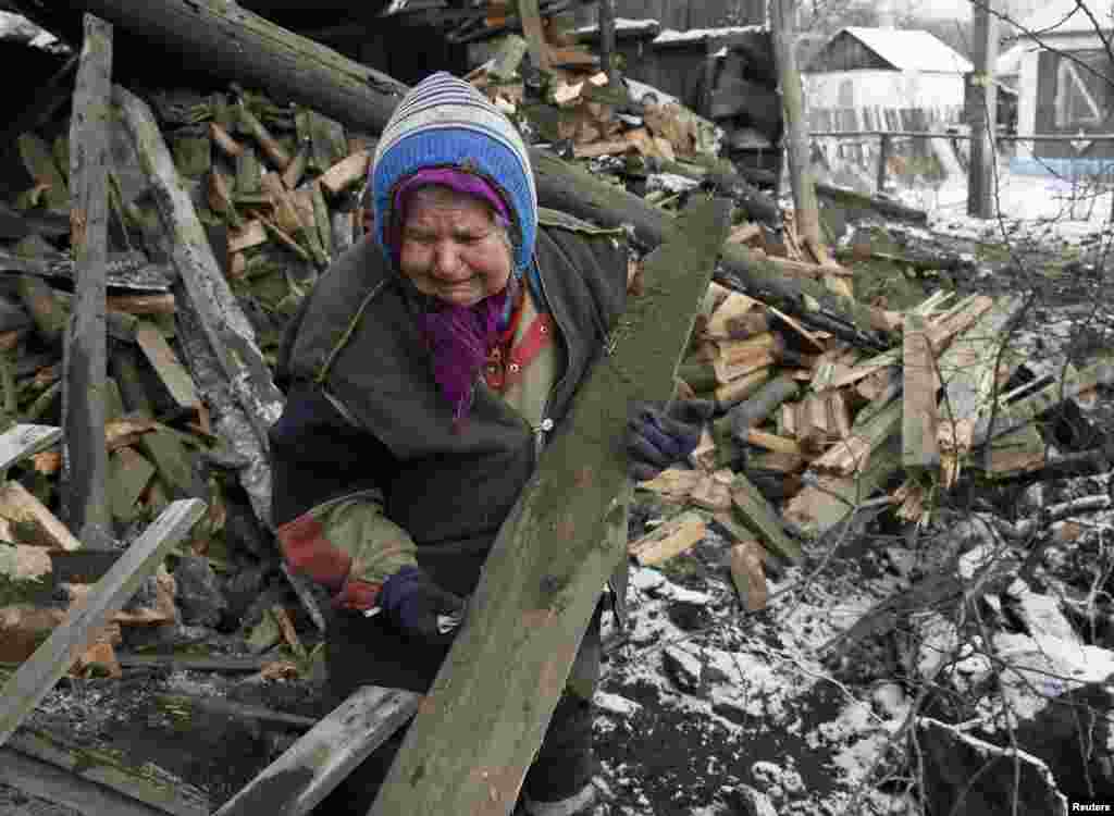 Seorang perempuan menangis saat mengangkat puing-puing dari rumahnya yang hancur dalam pertempuran antara pasukan pemerintah dan pemberontak pro-Rusia di kota Horlivka, Ukraina timur (10/2). (Reuters/Maxim Shemetov)
