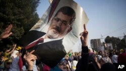 Seorang perempuan Mesir memegang potret presiden terguling Mohamed Morsi dalam sebuah protes di Kairo (1/11). 