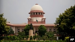 FILE - A gardener works on the lawns of the Supreme Court in New Delhi, India.