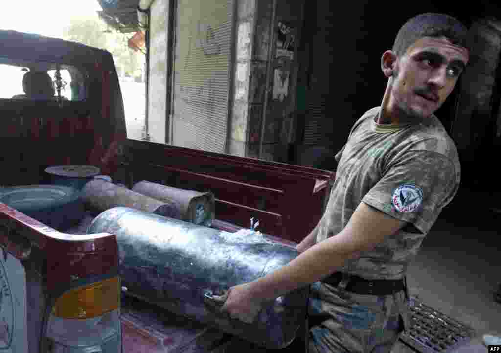 A Syrian rebel fighter unloads an Improvised Explosive Device (IED) from a pick up during fighting with government troops in the old city of Aleppo, September 28, 2012.