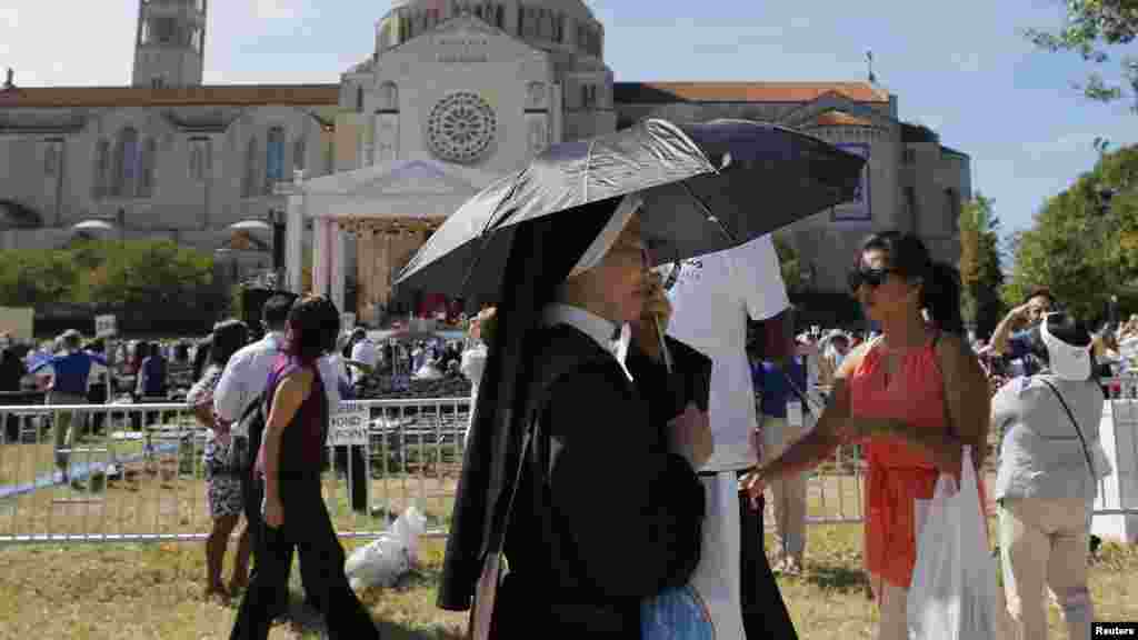 Une religieuse se couvre parmi d'autres personnes venues assister à la canonisation du moine Friar Junipero Serra par le pape François à la Basilique de l'Immaculée Conception à Washington, 23 septembre 2015.