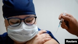 FILE - A medic at a regional hospital receives Russia's "Sputnik-V" vaccine shot against the COVID-19 disease in Tver, Russia, Oct. 12, 2020. 
