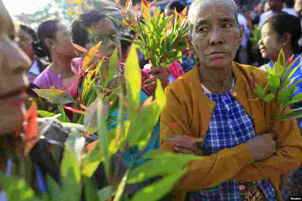 Family members hold leaves as they wait for political prisoners to be released from Insein prison in Rangoon, Burma, Dec. 31, 2013. 