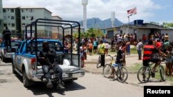 Des habitants regardent un policier passé lors d'une opération dans la favela de la Cité de Dieu à Rio de Janeiro, Brésil, le 20 novembre 2016.