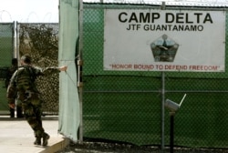 25 Ağustos 2005 yılına ait bu fotoğrafta bir ABD askeri, Küba'nın Guantanamo Koyu'ndaki askeri üste bulunan hapishanenin giriş kapısını kapatırken görüntülenmiş.