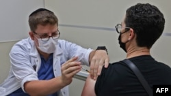 Un agent de santé israélien administre une troisième dose du vaccin Pfizer-BioNtech COVID-19 à un patient, au service de santé Maccabi à Jérusalem le 20 août 2021.