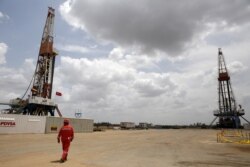 Un trabajador de un campo petrolero camina junto a las plataformas de perforación en un pozo de petróleo operado por la petrolera estatal venezolana PDVSA, en el cinturón del Orinoco. Abril 16, 2015. Foto: Reuters.