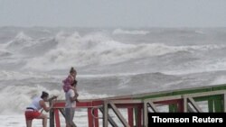 A family watches high swells from Hurricane Hanna from a jetty in Galveston, Texas