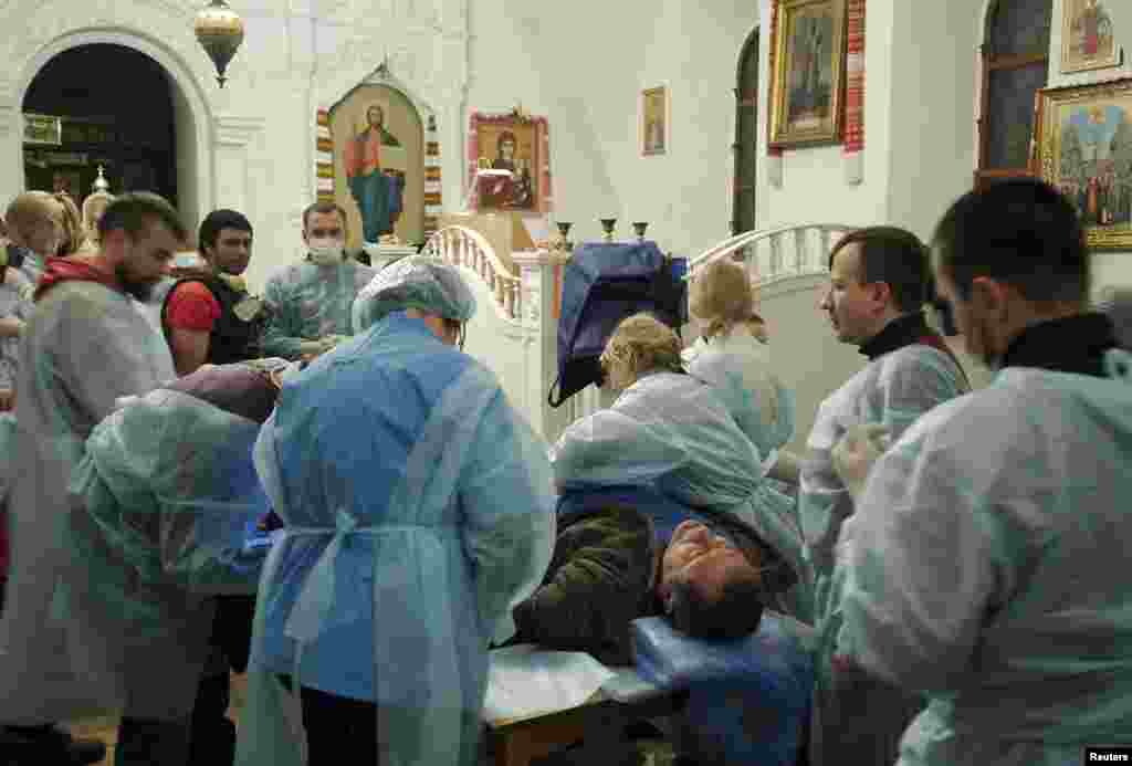 Para korban luka mendapat perawatan medis di dalam Katedral Mikhailovsky Zlatoverkhy Cathedral di Kyiv (19/2). (Reuters/Maks Levin)