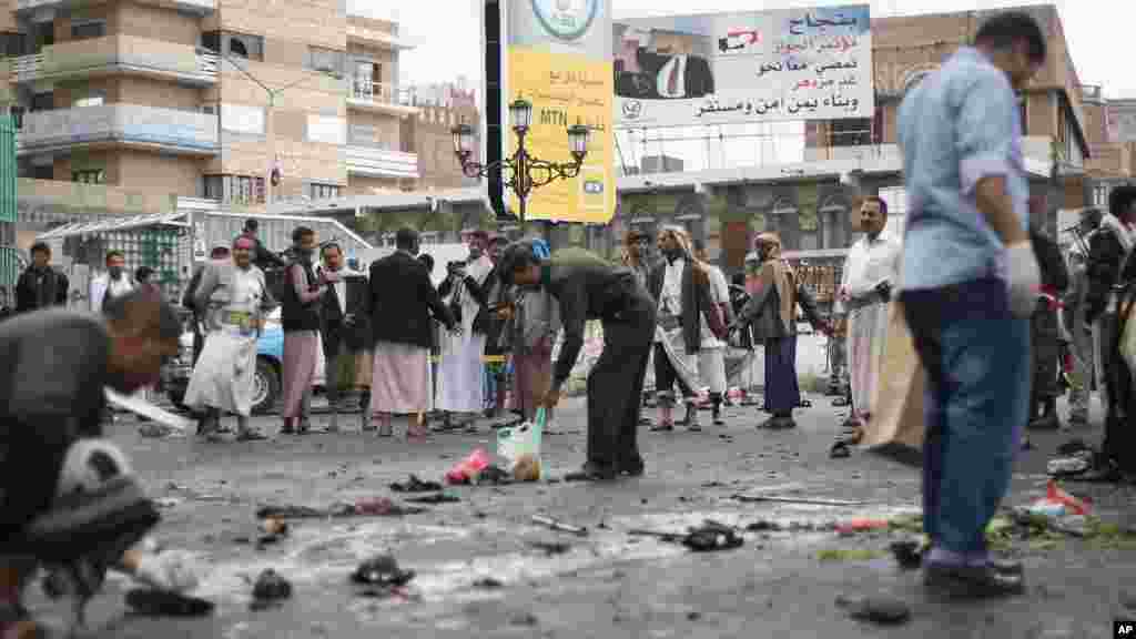 Des curieux contemplent les autorités de la sécurité prélevant les débris d’une explosion causée par un attentat suicide à Sanaa, Yémen, jeudi le 9 octobre 2014. AP Photo